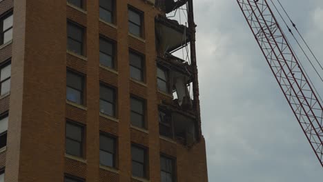 An-image-showing-the-demolition-of-a-high-rise-building-in-Youngstown,-Ohio,-with-significant-structural-damage-and-a-crane-visible-on-the-right