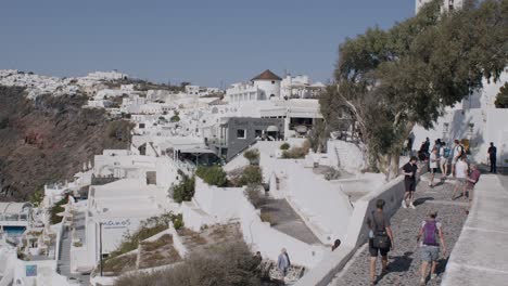 Touristen-Erkunden-Die-Charmanten-Weiß-Getünchten-Gebäude-Und-Kopfsteinpflasterstraßen-Von-Fira,-Santorini