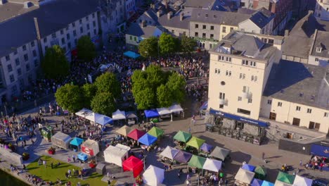 Aerial-pullback-from-Pegasus-parade-at-Spanish-Arch,-revealing-a-wide-angle-of-Galway-city