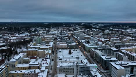 Aerial-pull-back-over-streets-in-downtown-Lahti,-gloomy,-winter-evening-in-Finland