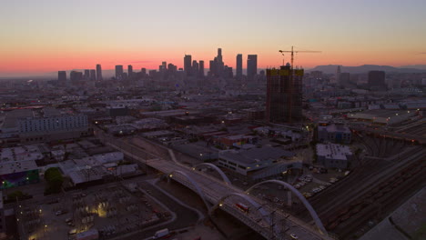 Aerial-view-of-downtown-Los-Angeles,-featuring-the-central-railway-station-with-the-city-skyline-illuminated-by-evening-colors,-highlighting-the-urban-connectivity-of-the-city