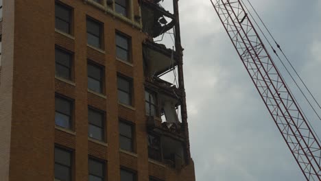 A-partially-demolished-building-in-downtown-Youngstown,-Ohio,-shows-exposed-floors-and-structural-damage,-with-a-crane-positioned-nearby