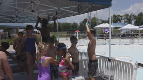 Niños-Disfrutando-De-Un-Día-Soleado-En-Una-Fiesta-En-La-Piscina-Bajo-Toldos-De-Sombra,-Sonriendo-Y-Jugando