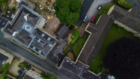 Experience-dynamic-descending-drone-footage-as-the-camera-moves-downward-over-Cirencester’s-buildings,-revealing-intricate-details-of-the-urban-landscape-and-architectural-features-from-above