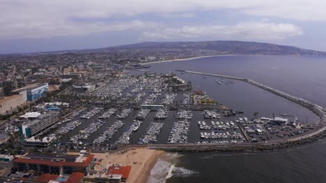 Wide-aerial-panning-shot-of-the-King-Harbor-Marina-towards-the-Palos-Verdes-peninsula-in-Redondo-Beach,-California