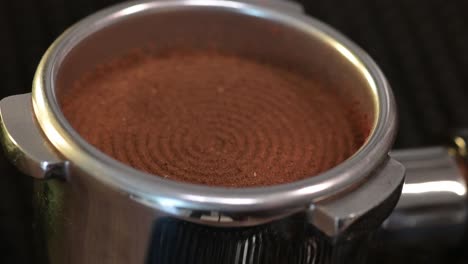 Close-up-tamping-freshly-grounded-coffee-beans,-close-up-of-tamper-in-process