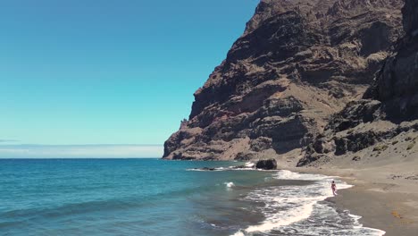 Idyllic-scene-of-a-woman-relaxing-unwinding-at-unspoiled-virgin-beach-in-Gran-Canaria,-Spain-during-summer-time-on-vacations