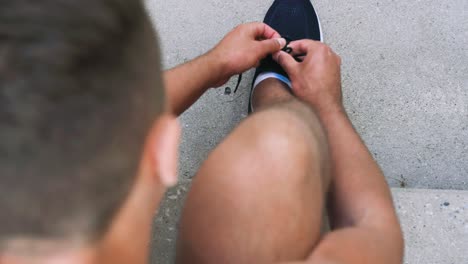 Man-Tying-Laces-of-His-Sneakers-on-Street.fitness,-sport-and-healthy-lifestyle-concept-man-tying-laces-of-his-sneakers-on-street