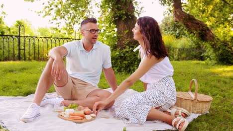 Happy-Couple-with-Food-Having-Picnic-on-Beach.leisure,-relationships-and-people-concept-happy-couple-with-food-eating-grapes-and-having-picnic-on-beach