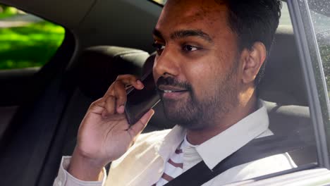 Male-Passenger-Calling-on-Smartphone-in-Taxi-Car.transport,-business-and-technology-concept-happy-smiling-indian-male-passenger-or-businessman-using-voice-command-recorder-on-smartphone-on-back-seat-of-taxi-car