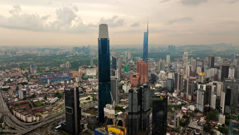 Aerial-sunset-view-of-tall-skyscrapers-dominating-Kuala-Lumpur-skyline,-Malaysia