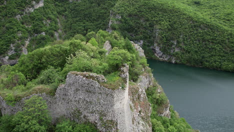 Aerial-view-of-old-castle-on-top-of-a-hill-with-hydroelectric-power-plant