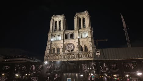 Front-facade-with-the-main-two-towers-of-the-Notre-Dame-catholic-cathedral-at-night-under-reconstruction-in-Paris,-France