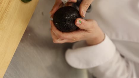 Chef-Splitting-A-Ripe-Avocado-With-A-Sharp-Knife-In-Hands