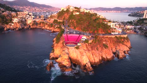 Aerial-orbit-overlooking-the-Symphony-of-the-Sea-Amphitheater-and-the-Acapulco-cliffside-view-at-sunset