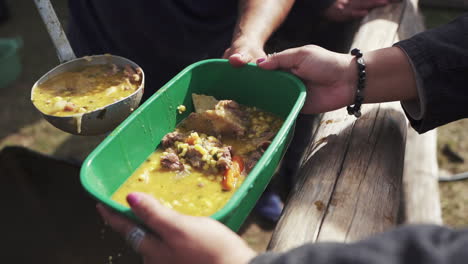 Filling-Up-a-Container-with-Typical-Argentine-Locro-Stew,-Slow-Motion