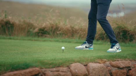 Close-up-of-Golfer-hitting-his-driver-off-the-tee-box-on-iconic-Irish-links-golf-course-in-slow-motion