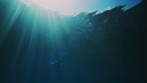 Funkelndes-Licht-Tanzt-über-Das-Wasser,-Während-Sich-Wellen-Bilden-Und-Der-Surfer-Untertaucht-Und-Sein-Brett-Nach-Unten-Drückt,-Um-Der-Kraftvollen,-Turbulenten-Welle-Zu-Entkommen