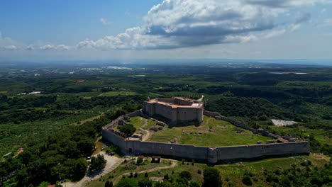 Epic-aerial-view-of-the-Chlemoutsi-Castle-Museum-in-Greece-with-wide-green-forests-and-fields-around,-slow-motion-on-a-cloudy-sunny-day