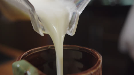 Beautiful-slow-motion-shot-while-pouring-a-piña-colada-cocktail-in-a-ceramic-glass-with-a-handmade-and-cultural-design