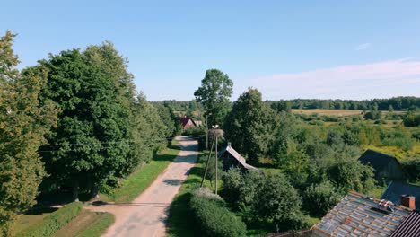 Ruhige-Aussicht-Auf-Ein-Baltisches-Dorf-In-Lettland-Mit-Zwei-Störchen,-Die-In-Ihrem-Großen-Nest-Auf-Einem-Strommast-Thront