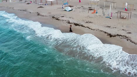 Einsames-Mädchen-Steht-Am-Strand-Mit-Wellen,-Die-Auf-Den-Sand-Treffen