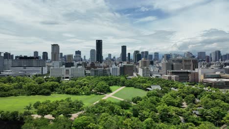 Luftaufnahme-Einer-Stadtlandschaft-Von-Osaka-Mit-Gebäuden-Und-üppigen-Parkbäumen-Im-Vordergrund