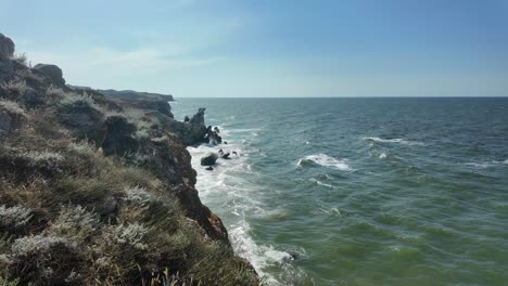 The-coastline-of-Crimea-shows-waves-crashing-against-rocky-outcrops,-highlighting-the-natural-beauty-of-the-Sea-of-Azov-during-a-serene-sunset