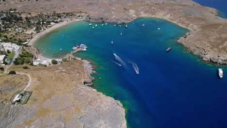 Bright-blue-bay-in-Greece-with-boats,-captured-from-a-drone-perspective