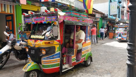 Tourist-in-Motochiva,-Colombian-Tuk-Tuk-Vehicle,-Waving-to-Camera-While-Visiting-Guatape-Town