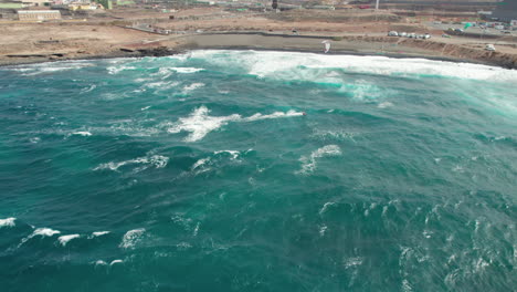 Fantastic-drone-shot-of-a-group-of-people-kitesurfing-on-a-windy-day-with-big-waves