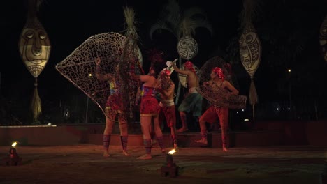 Balinese-African-Rhythm-Fire-Dance-Performance-Show-at-Bali-Safari-And-Marine-Park,-Indonesia---Tribal-Men-and-Women-Performers-Dancing-on-Stage-Surrounded-by-Huge-Face-Totems