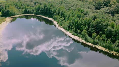 Luftaufnahmen,-Die-Die-Atemberaubende-Spiegelung-Der-Wolken-In-Einem-Ruhigen-See,-Umgeben-Von-Dichtem-Wald,-Einfangen