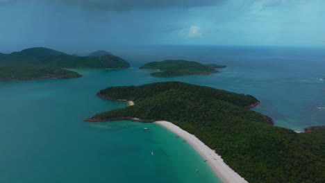 Whitehaven-Beach-white-sand-aerial-drone-Whitsundays-Island-Airlie-National-Park-Australia-AUS-QLD-rain-cloudy-blue-sky-outer-Great-Barrier-Reef-clear-blue-aqua-ocean-boat-yachts-backwards-up-motion