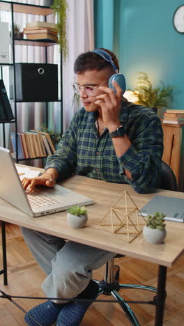 Business-man-listening-music-through-wireless-headphones-relaxing-taking-a-break-laptop-on-table