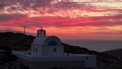 Feuerrote-Wolken-Kontrastieren-Mit-Der-Kirche-Der-Heiligen-Weisheit-In-Donousa,-Griechenland-Bei-Sonnenuntergang