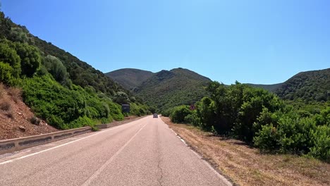 Scenic-across-countryside,-road-weaves-between-emerald-hills