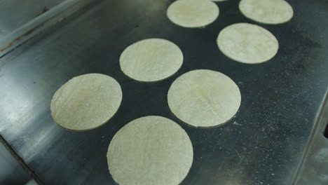 Beautiful-general-shot-of-a-set-of-Mexican-tortillas-cooking-on-a-griddle-inside-a-restaurant