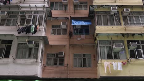 Fachada-De-Un-Edificio-De-Apartamentos-Residenciales-En-Hong-Kong-Con-Ventanas,-Balcones-Y-Unidades-De-Aire-Acondicionado,-Inclinadas-Hacia-Arriba.