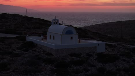 Eine-Drohne-Senkt-Sich-Herab-Und-Neigt-Sich-Nach-Oben,-Um-Bei-Einem-Wunderschönen-Sonnenuntergang-Die-Kirche-Der-Heiligen-Weisheit-In-Donousa,-Griechenland-Zu-Errichten