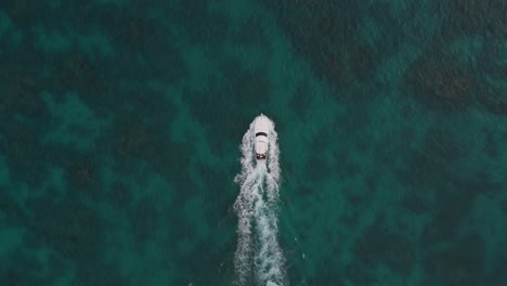 Drone-top-down-overview-tracking-follows-yacht-speedboat-in-green-blue-sandy-reef-waters