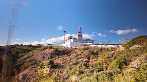 Ponta-da-Piedade-Lighthouse-on-cliff-with-blue-skies-in-Lagos,-Algarve,-Portugal---Timelapse