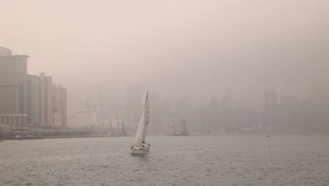 Blick-Auf-Das-Wasser-Eines-Bootes,-Das-In-Der-Nähe-Der-Küste-Der-Stadt-Hongkong-Segelt,-Mit-Smog-Am-Himmel,-Breite-Panoramaaufnahme