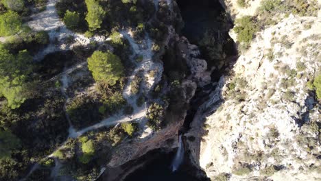 Waterfall-between-mountains,-aerial-top-down-view,-national-park-Valencia-Spain