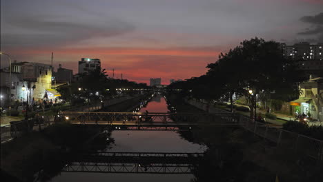 A-serene-and-picturesque-scene-unfolds-as-the-sun-dips-below-the-horizon,-casting-a-warm-golden-glow-over-a-tranquil-city-canal