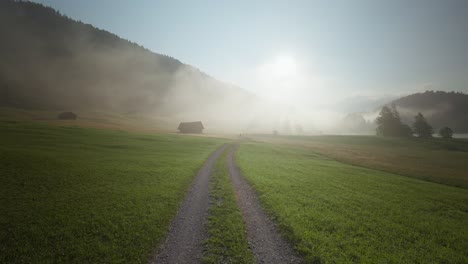 Ein-Biker-Fährt-An-Einem-Nebligen-Morgen-In-Der-Nähe-Des-Wagenbrüchsees-Einen-Gewundenen-Feldweg-Durch-Grüne-Felder-Hinunter