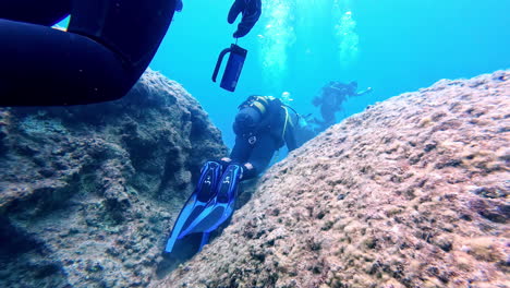 Free-diver-under-the-water-exploring-the-ground-of-the-ocean-in-Greece-with-diving-suit,-slow-motion-and-copy-space