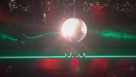 Illuminated-Disco-ball-hanging-in-front-of-Chandelier