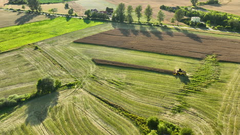 Drone-footage-of-a-combine-harvester-moving-through-a-crop-field-during-harvest,-showing-the-division-between-harvested-and-remaining-crops