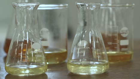 Tilt-down-to-a-close-up-shot-of-conical-flasks,-which-has-yellow-solution-in-them